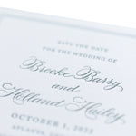 A close-up of a personalized stationery wedding invitation features elegant cursive text reading “Save the date for the wedding of Brooke Barry and Holland Hailey, October 1, 2023, Atlanta, Georgia.”.