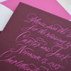 Maroon and pink wedding invitation with cursive text on a white background