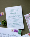 Wedding invitation card with stamps and a small plant on a textured surface