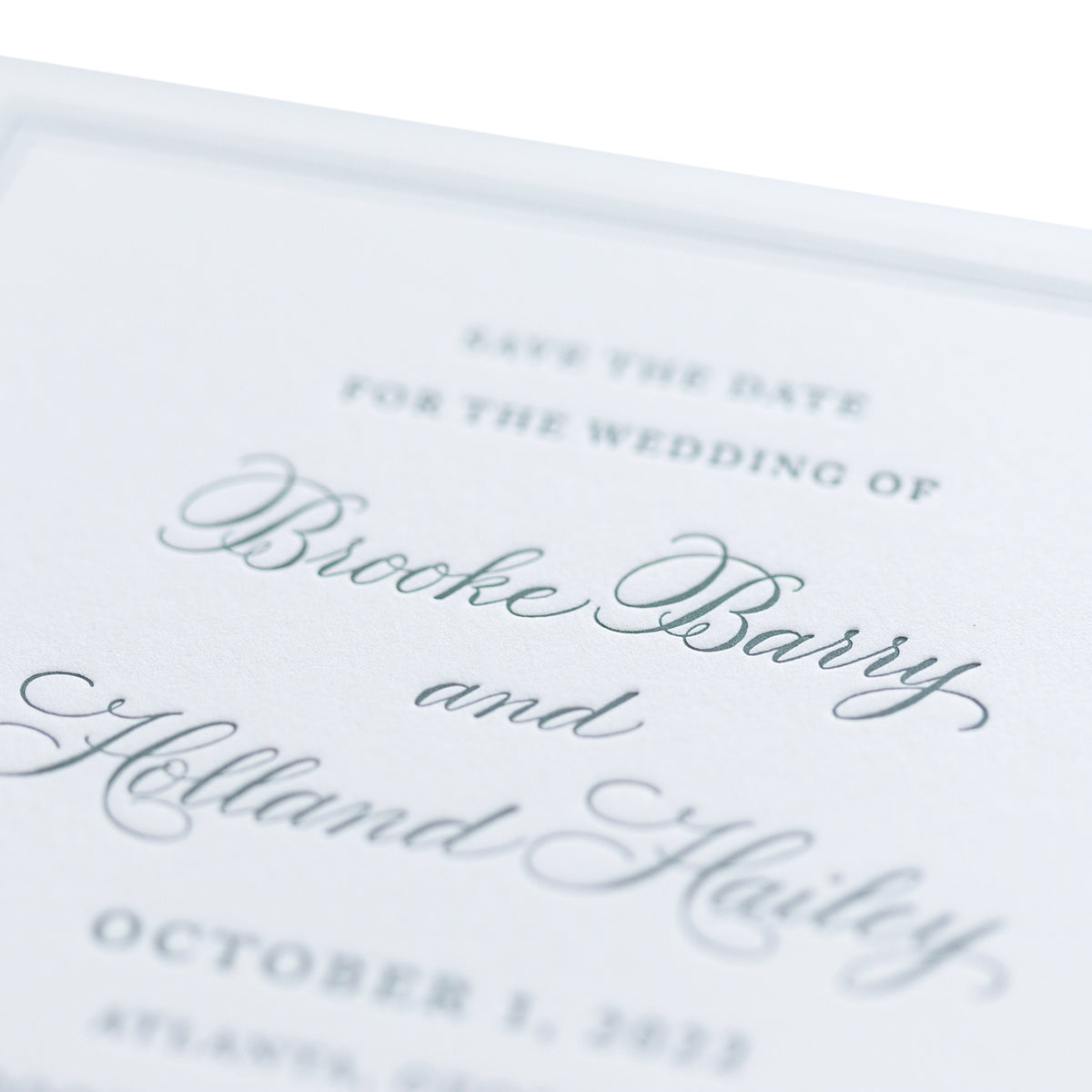 A close-up of a personalized stationery wedding invitation features elegant cursive text reading “Save the date for the wedding of Brooke Barry and Holland Hailey, October 1, 2023, Atlanta, Georgia.”.