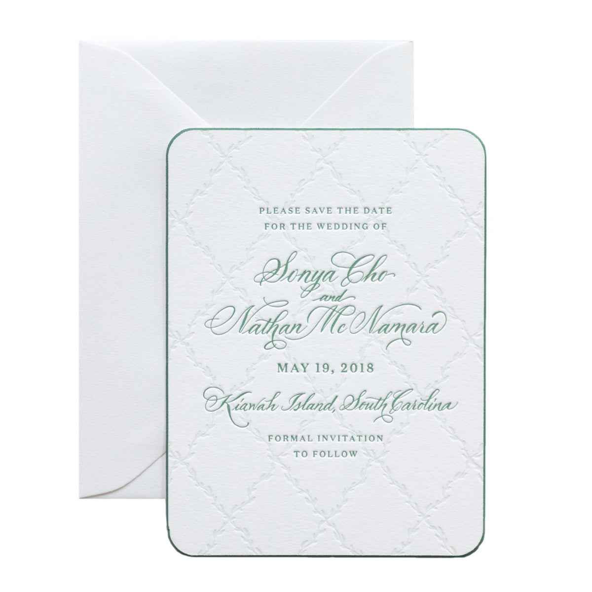 A white letterpress wedding save-the-date card with elegant green script font announces the wedding of Sonya Cho and Nathan McNamara on May 19, 2018, in Kiawah Island, South Carolina. An envelope sits behind this personalized paper keepsake.
